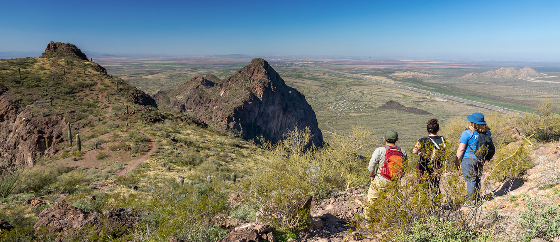 A trio of hikers at the peak of Hunter's Trail, looking out over the land below