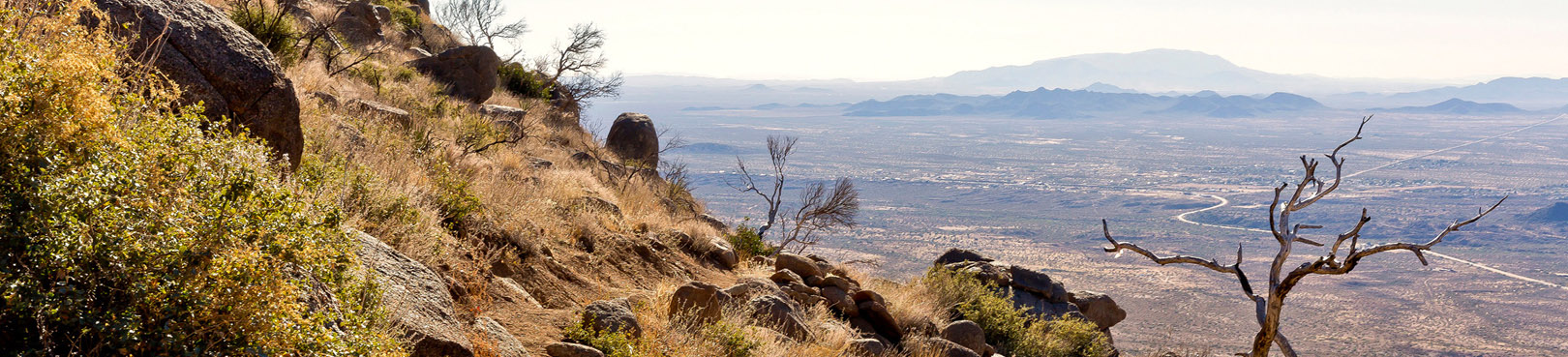 The midday view from high on a desert trail to the valley in the distance below.