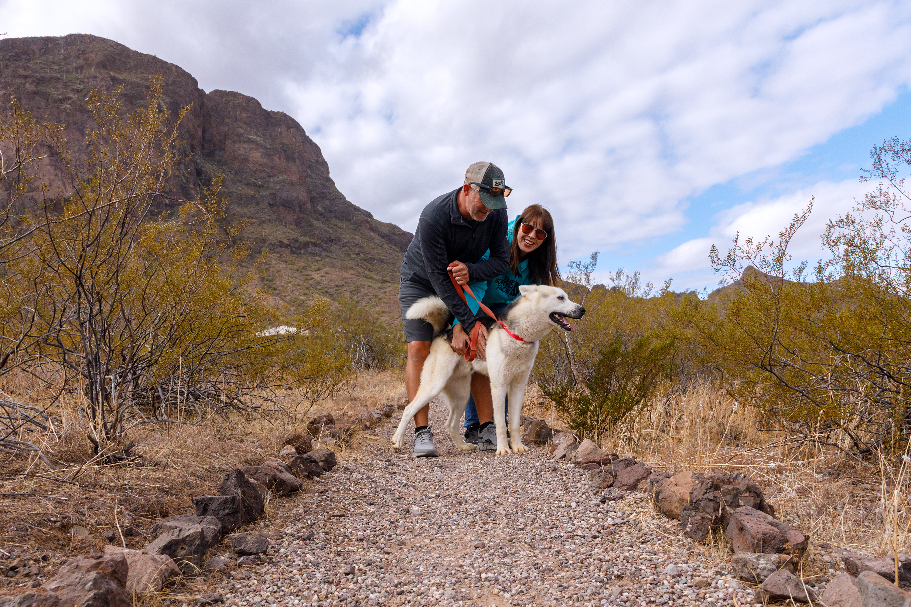 A couple with a white dog on the trail at Picacho Peak State Park
