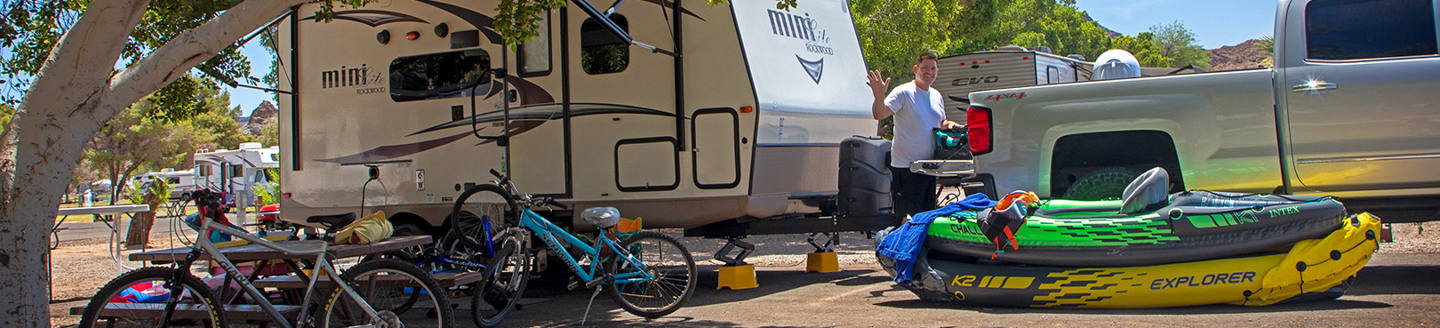 An RV campsite with a variety of outdoor toys including mountain bikes and inflatable kayaks.
