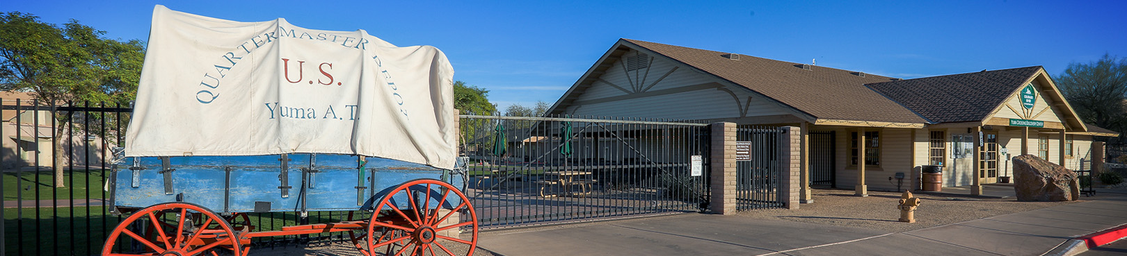 A red, white, and blue covered wagon sits just outside the historic US Quartermasters depot in Yuma.