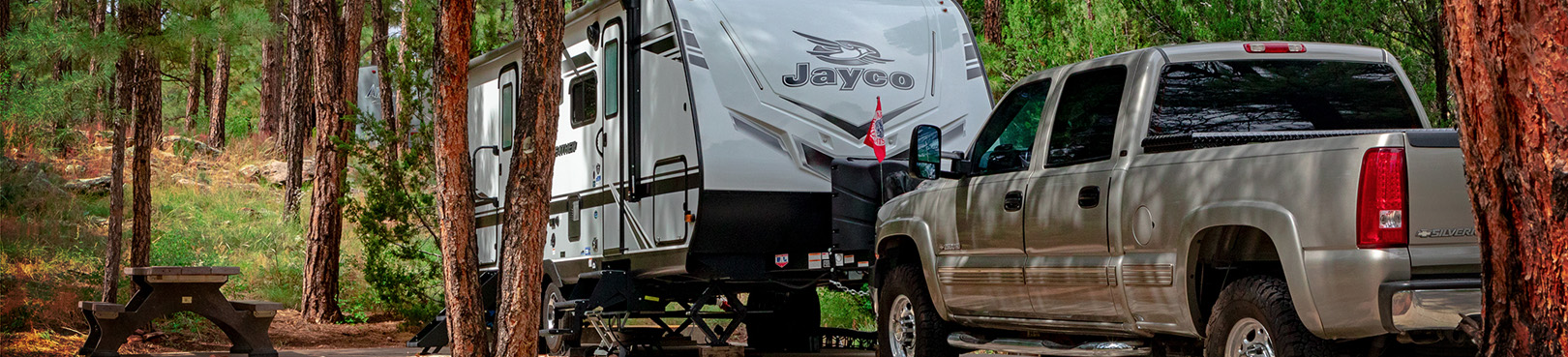 Pine trees partially obscure an RV and a truck at one of Fool Hollow's popular forest campsite locations.