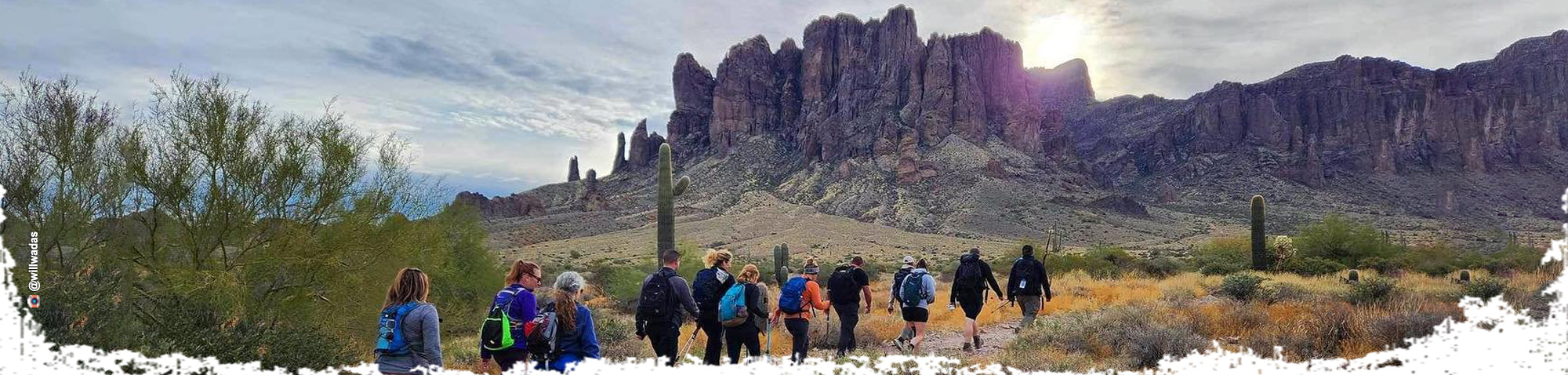 A group of hikers on a trail that ascends into the Superstition Mountains.