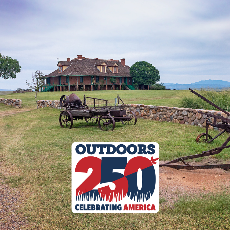 A photo of a historic house set in a grassy area with antique farming equipment in the foreground. Includes a graphic overlay "Outdoors250."
